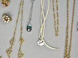 many different types of necklaces and earrings on the table
