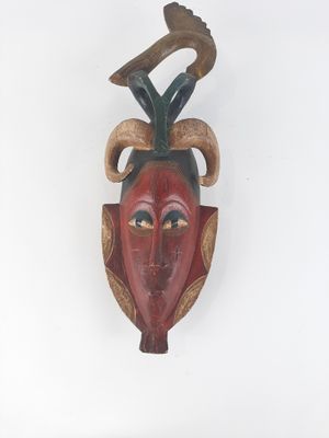 a wooden mask hanging on the wall with a bird on it