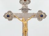 silver and gold crucifix with blue stones on a white background