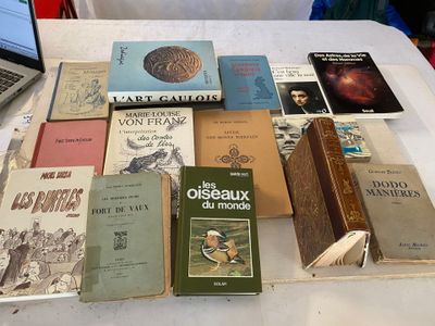 de nombreux livres posés sur une table, avec un ordinateur portable en arrière-plan