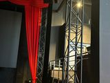 a man that is standing on a stage in front of a red curtain