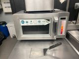 a silver microwave sitting on a counter with a spatula in front of it