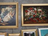 many framed pictures on the wall next to a vase of flowers