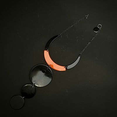 un collier noir et orange posé sur une surface noire