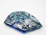 un objet en verre bleu et vert posé sur une surface blanche