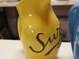 yellow and blue ceramic pitchers sitting on a counter in a kitchen