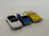 four toy cars are lined up in a row on a white surface