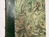 un vieux livre à la couverture verte posé sur une table blanche
