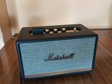 a small blue and black speaker sitting on a wooden table