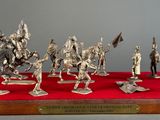 silver figurines of knights on horses and riders on a red surface