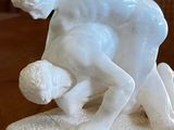 a statue of a man wrestling a woman on a table