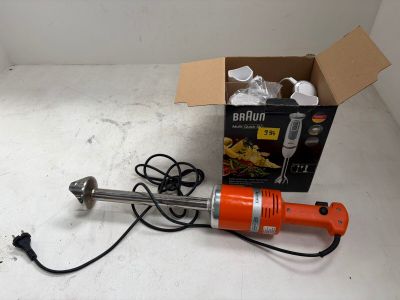 une perceuse électrique orange posée par terre à côté d'une boîte