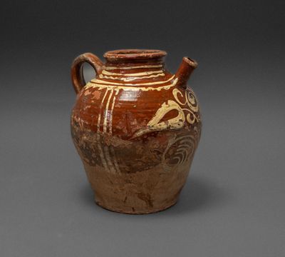a brown vase with a design on it on a gray surface
