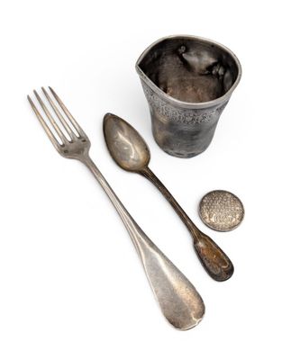 a silver cup with spoons and a fork next to it
