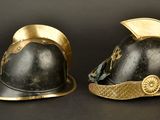 two helmets with gold trims are sitting on a black surface
