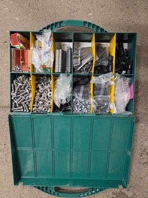 une boîte verte remplie d'un assortiment de vis et d'écrous
