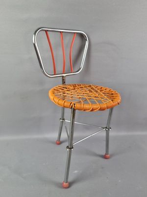 une chaise en métal avec une assise en osier sur fond gris