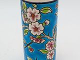 a blue vase with pink flowers on it on a white surface
