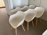 several white chairs are lined up against a wall in a room