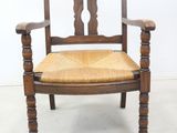 an image of a wooden chair with a wicker seat and arm rest
