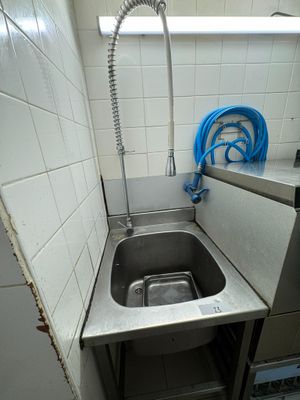 a sink in the corner of a kitchen with a hose in it