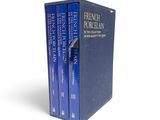 a set of three books sitting on top of each other on a white surface