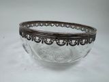 a glass bowl with a metal rim on a white surface
