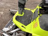 a close up of a yellow snowmobile parked on the side of the road