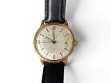gros plan d'une montre sur une surface blanche avec un bracelet noir
