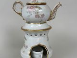 a white tea pot with a cup in it