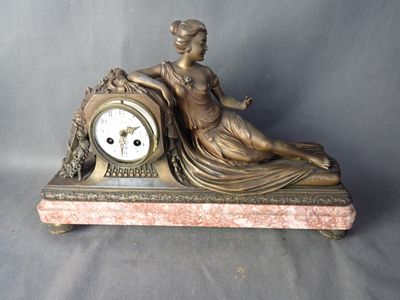 une statue en bronze représentant une femme assise sur une horloge