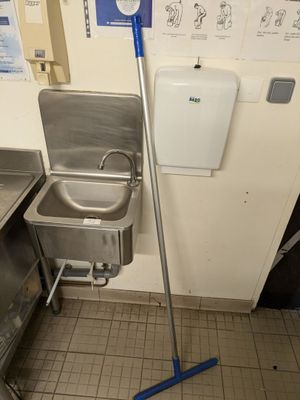 a metal sink and a blue mop in a public restroom