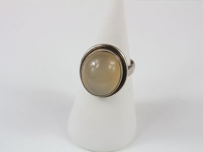 silver ring with a brown stone in the middle of it on a white napkin