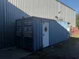 un conteneur d'expédition bleu posé devant un immeuble