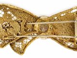 bow brooch with a gold tone finish and a clear crystal center