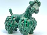une petite statue de chien verte posée sur une surface blanche