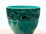 a green bowl sitting on top of a wooden table