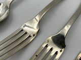 five forks and two spoons on a white table