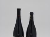 deux bouteilles de vin rouge sont posées sur une surface blanche