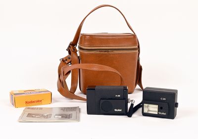 un sac en papier brun, un appareil photo et quelques autres objets posés sur une surface blanche