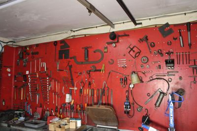 a red wall with a bunch of tools hanging on it