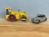 une petite voiture à côté d'un petit tracteur, posés sur une table