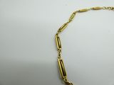a gold necklace with a long link on a white surface