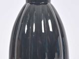 un vase noir posé sur une surface blanche, avec un fond blanc