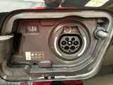 a close up of a car ' s fuel pump with a person holding a cell phone