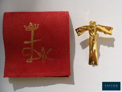 une croix en or sur un tissu rouge, à côté d'un crucifix en or