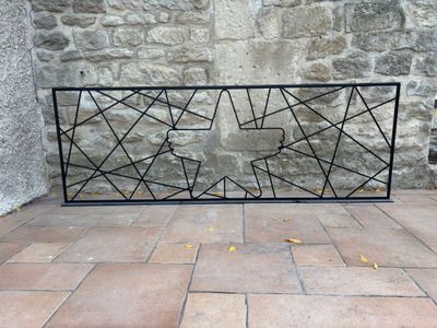 une clôture en fer noir posée sur un sol en briques, à côté d'un mur en pierre
