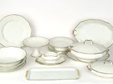 un service de table blanc et doré comprenant des assiettes, des bols et des plateaux