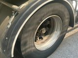 a green semi truck with a flat tire parked on the side of the road