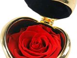 une boîte en forme de cœur dorée contenant une rose rouge